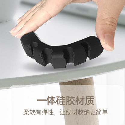 Wirenest – Hand bending a black silicone cord clip over a tabletop edge to show its soft, flexible material