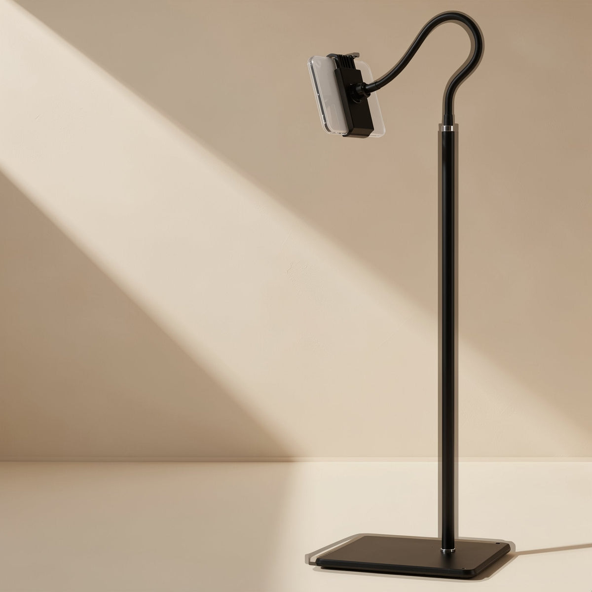 Risepost – Black floor stand with a curved gooseneck arm and phone clamp on a square base against a beige wall
