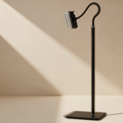 Risepost – Black floor stand with a curved gooseneck arm and phone clamp on a square base against a beige wall