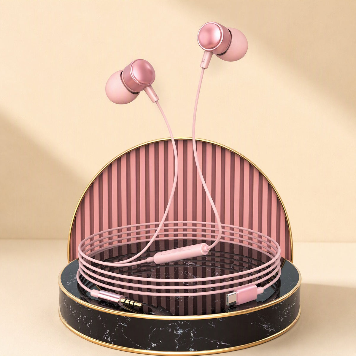 Earchime – Pink in-ear headphones with cable coiled on a marble and gold display stand with Type-C and 3.5mm ends