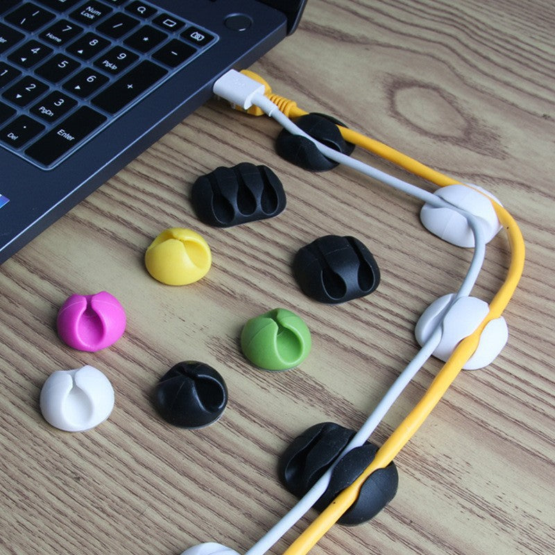 Cordscape – Assorted cable clips in black, white, yellow, pink and green routing white and yellow cables beside a laptop