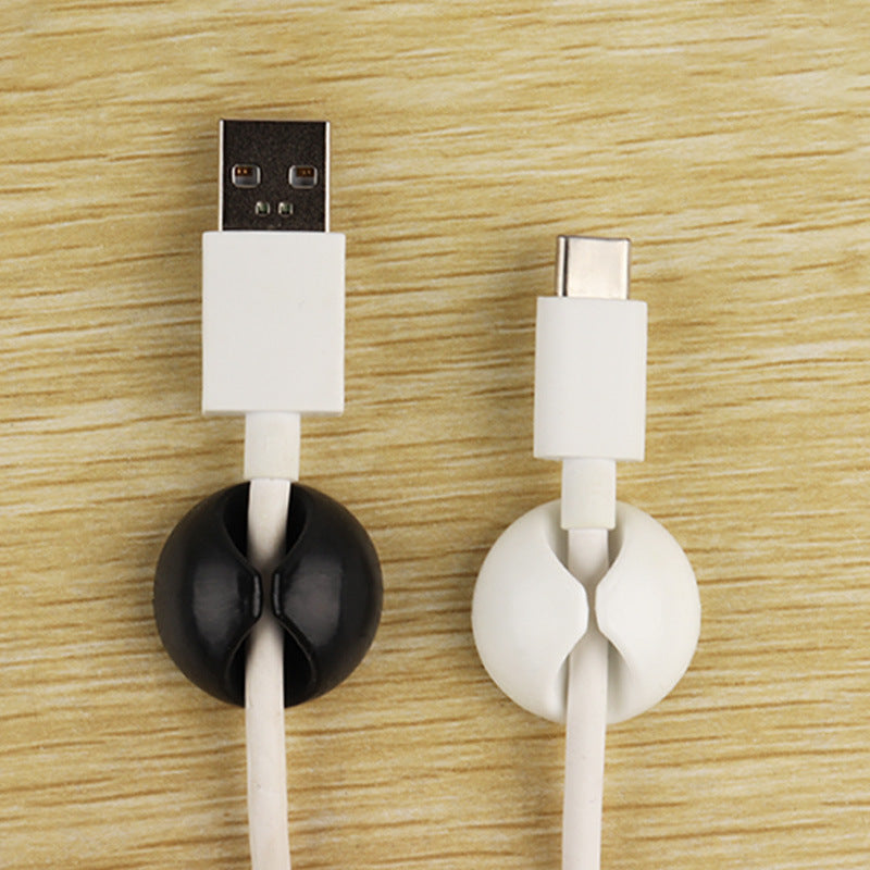 Cordscape – Black and white round clips each holding a white USB cable, shown from above on a wood surface