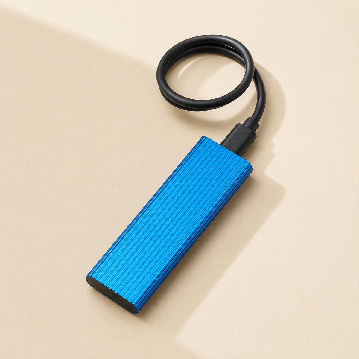Ministore – Blue ribbed external drive with attached black USB-C cable coiled above it on a beige background