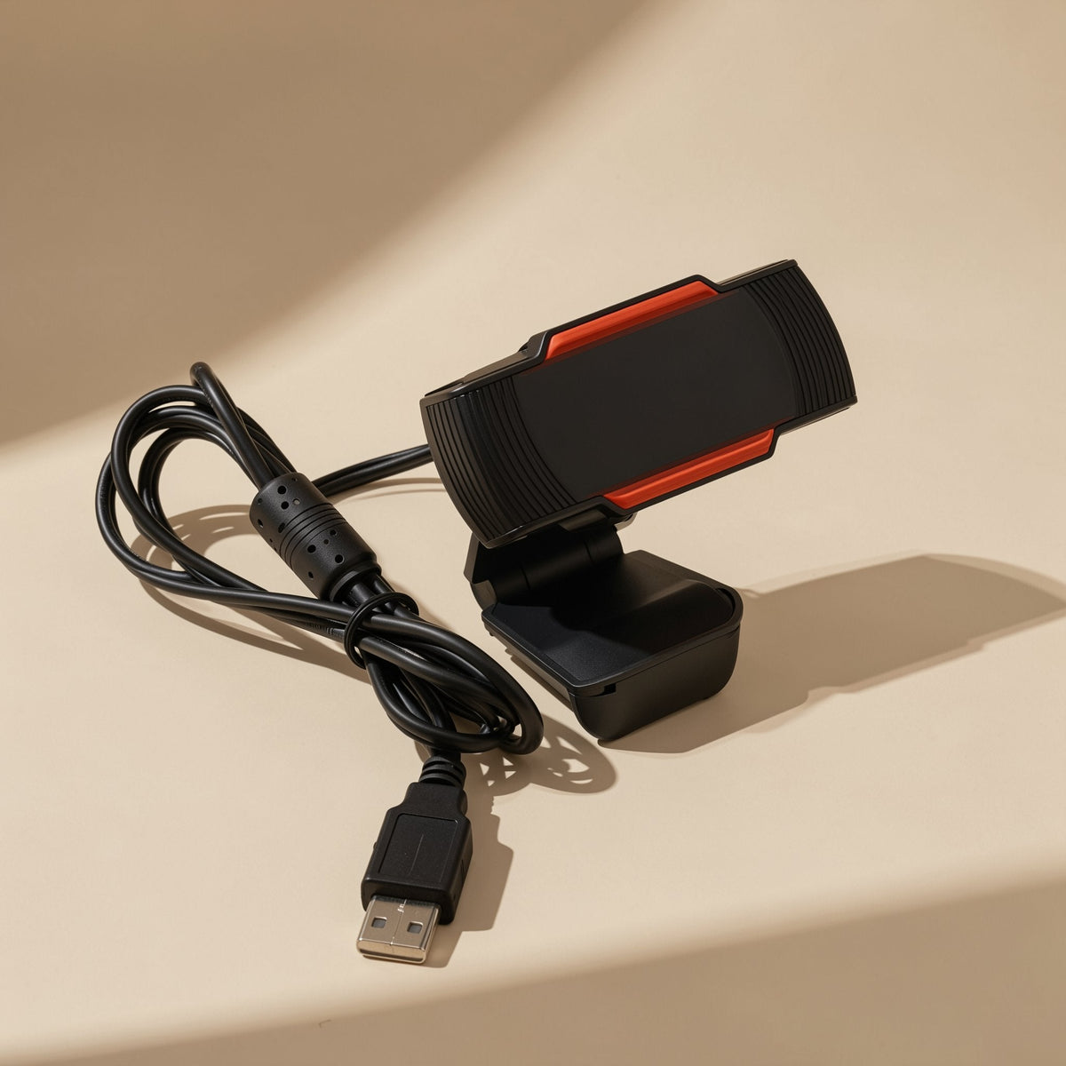 Talklens – Webcam with coiled black USB cable and ferrite bead, USB-A plug in front on a beige background