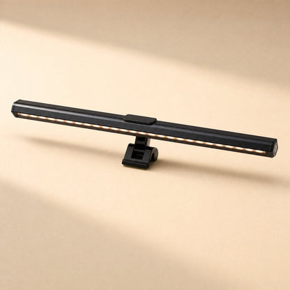 Deskbeam – Side view of the black lamp bar on its clip mount, with warm LED strip lit along the underside