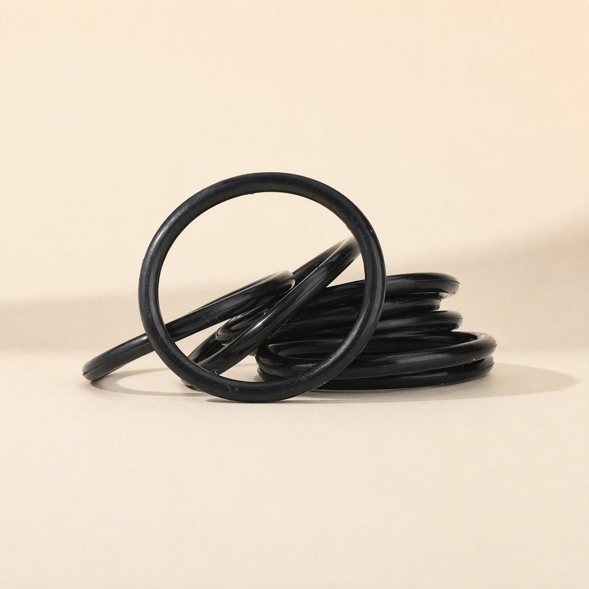 Miccushion Condenser Microphone Shock Mount Bracket – stack of black replacement elastic bands on a beige background