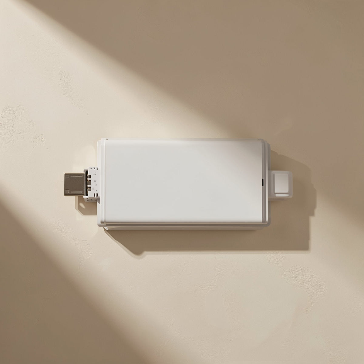 Sixport – Top-down view of the white reader's flat face with a Type-C plug on the left, in angled light