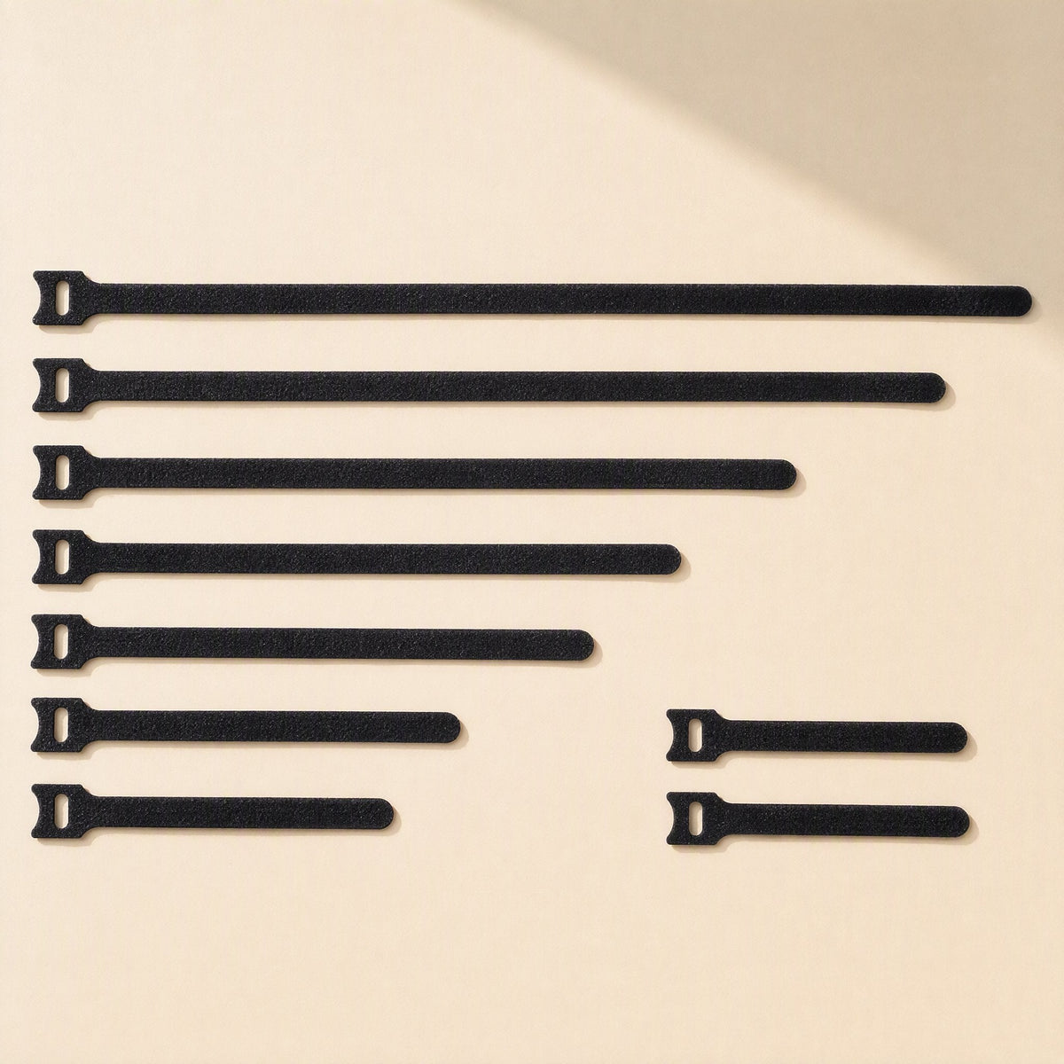 Softbind Nylon Hook-and-Loop Cable Tie in black, shown in seven lengths on a cream background