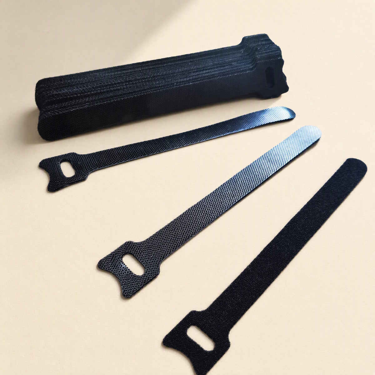 Softbind – Stack of black hook-and-loop ties with three ties laid out, showing the hook side, loop side and eyelet end
