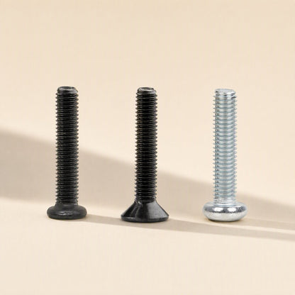 Microbite – Three black and silver machine screws with pan, flat and countersunk heads standing upright on a cream background