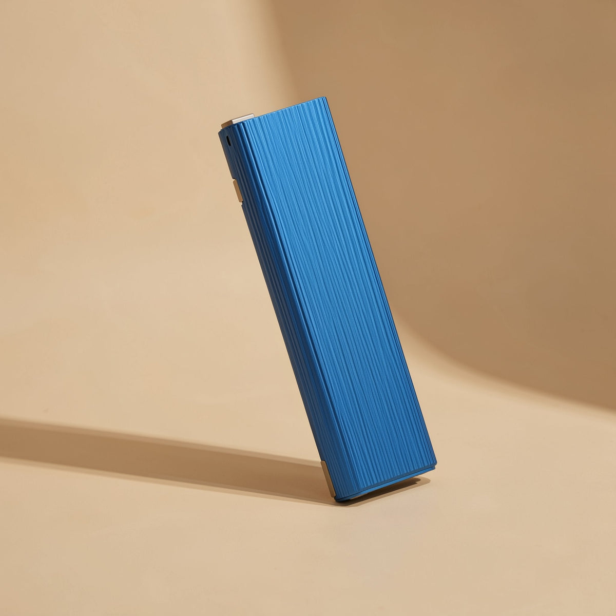 Swiftbyte Metal Portable Solid State Drive – blue ribbed metal portable SSD leaning at an angle against a curved tan backdrop