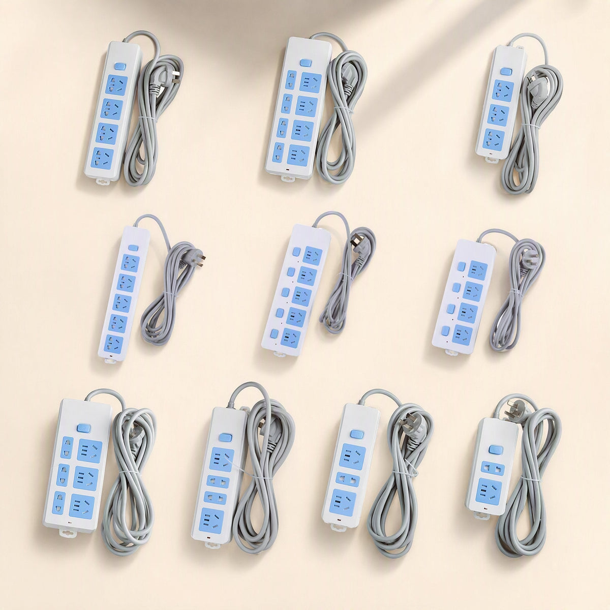 Cordcraft – Ten white and blue power strips with grey cords coiled beside them, arranged in rows on a beige surface