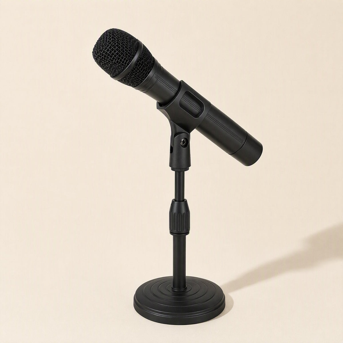 Voicelift – Black handheld microphone held in the clip of a round-based desktop stand against a cream background