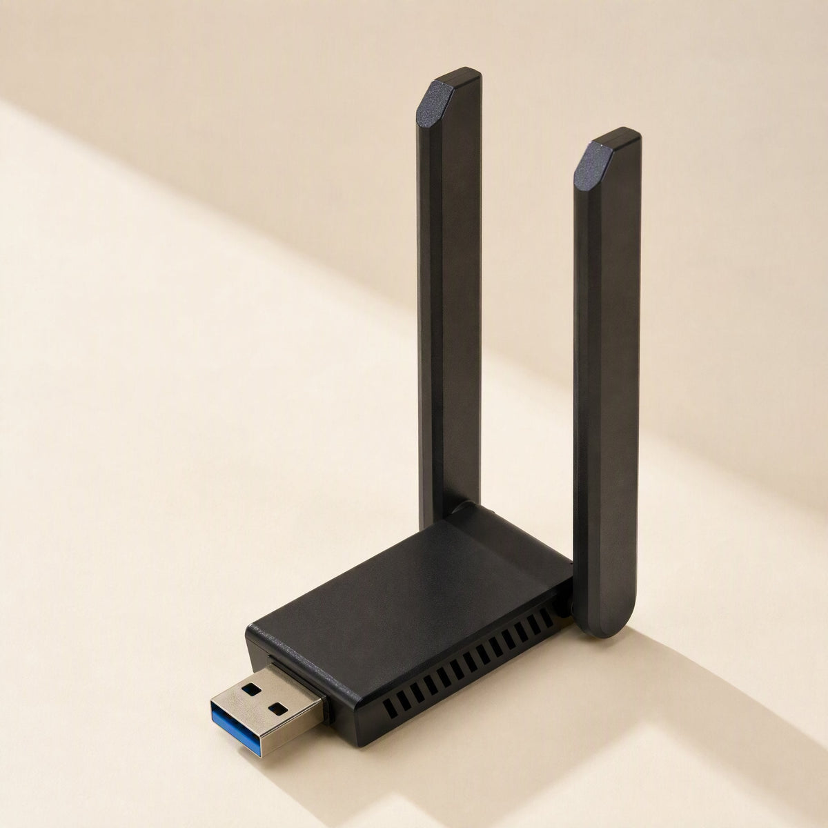 Twinsignal – Black USB wireless adapter with two upright antennas and side vents standing on a cream surface