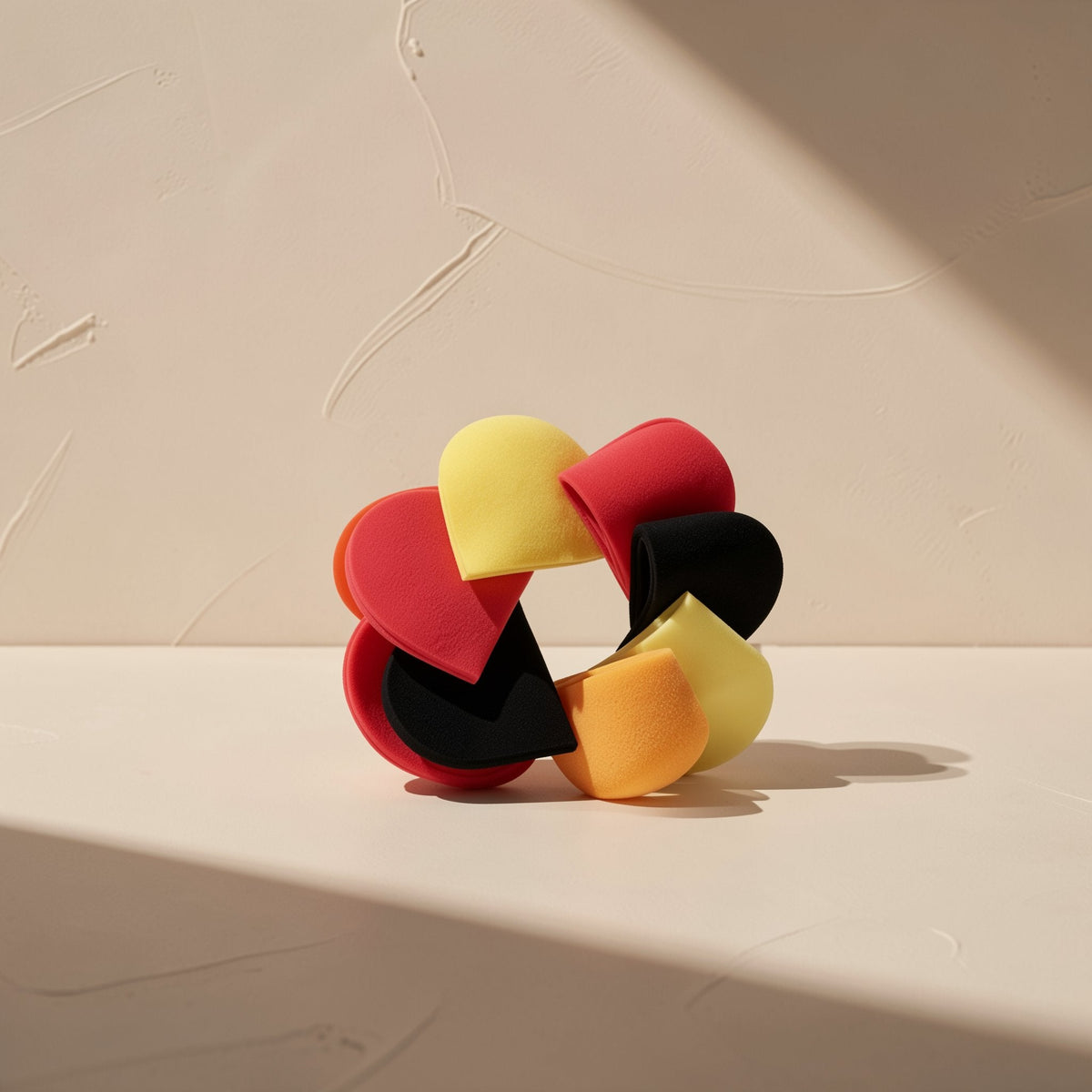 Curvehush – Colorful U-shaped sponge pieces in red, yellow, black and orange arranged in a ring