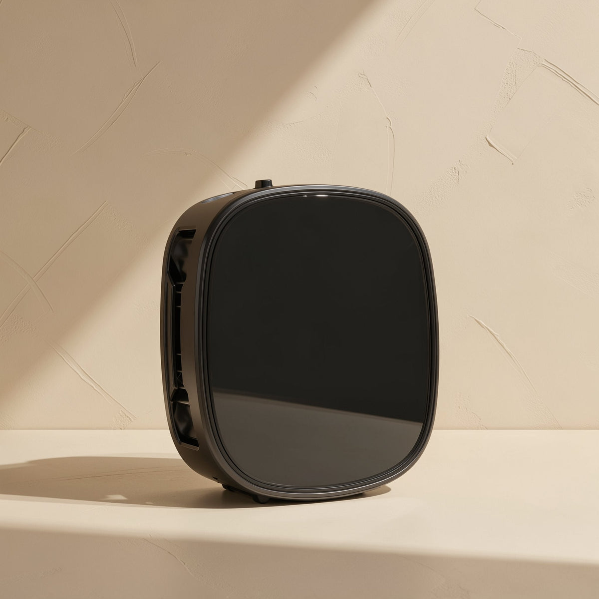 Chillport – Back of a black rounded-square phone cooler with glossy panel and side vents on a beige shelf