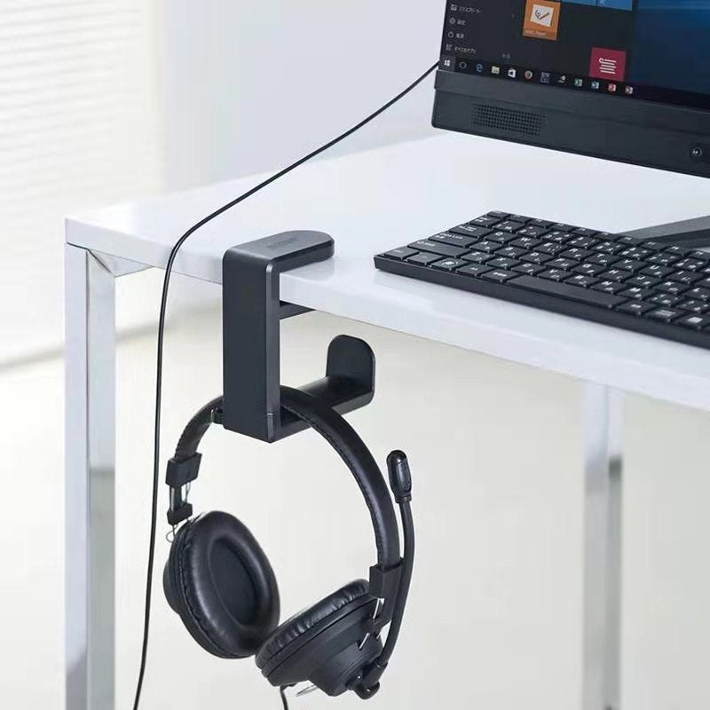 Perchspin Headset Stand – black clip-on headphone stand on a white desk beside a keyboard, holding a headset with microphone