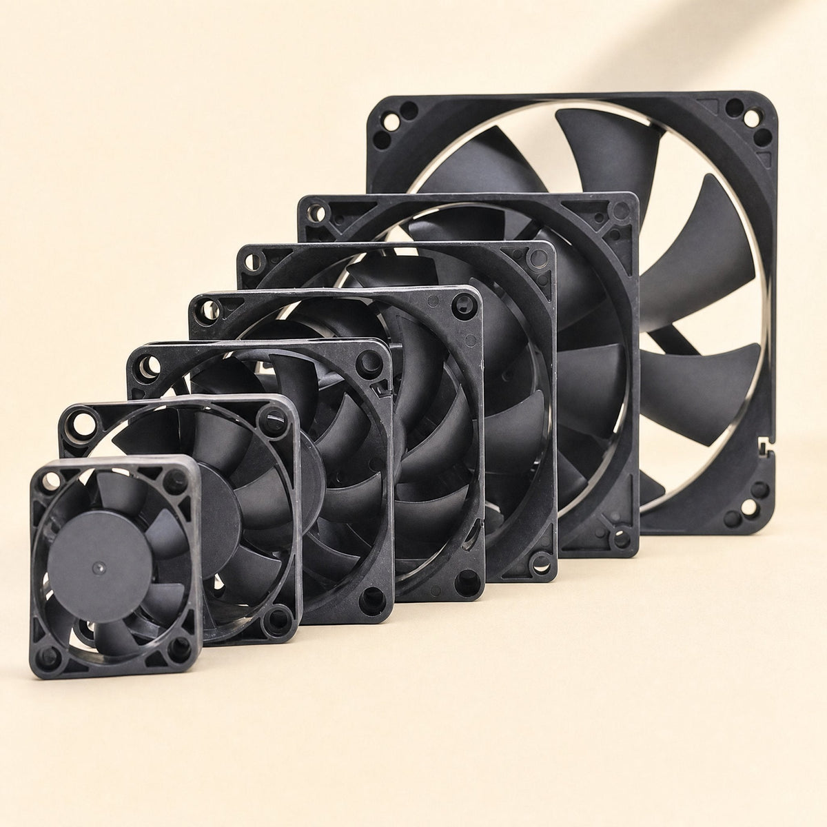 Breezeball 12cm Cooling Fan lined up beside smaller black fans in graduated sizes on a cream background