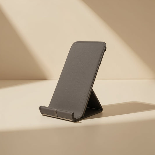 Metalrest – Dark gray fabric-covered foldable stand angled upright with a front lip, in soft diagonal sunlight