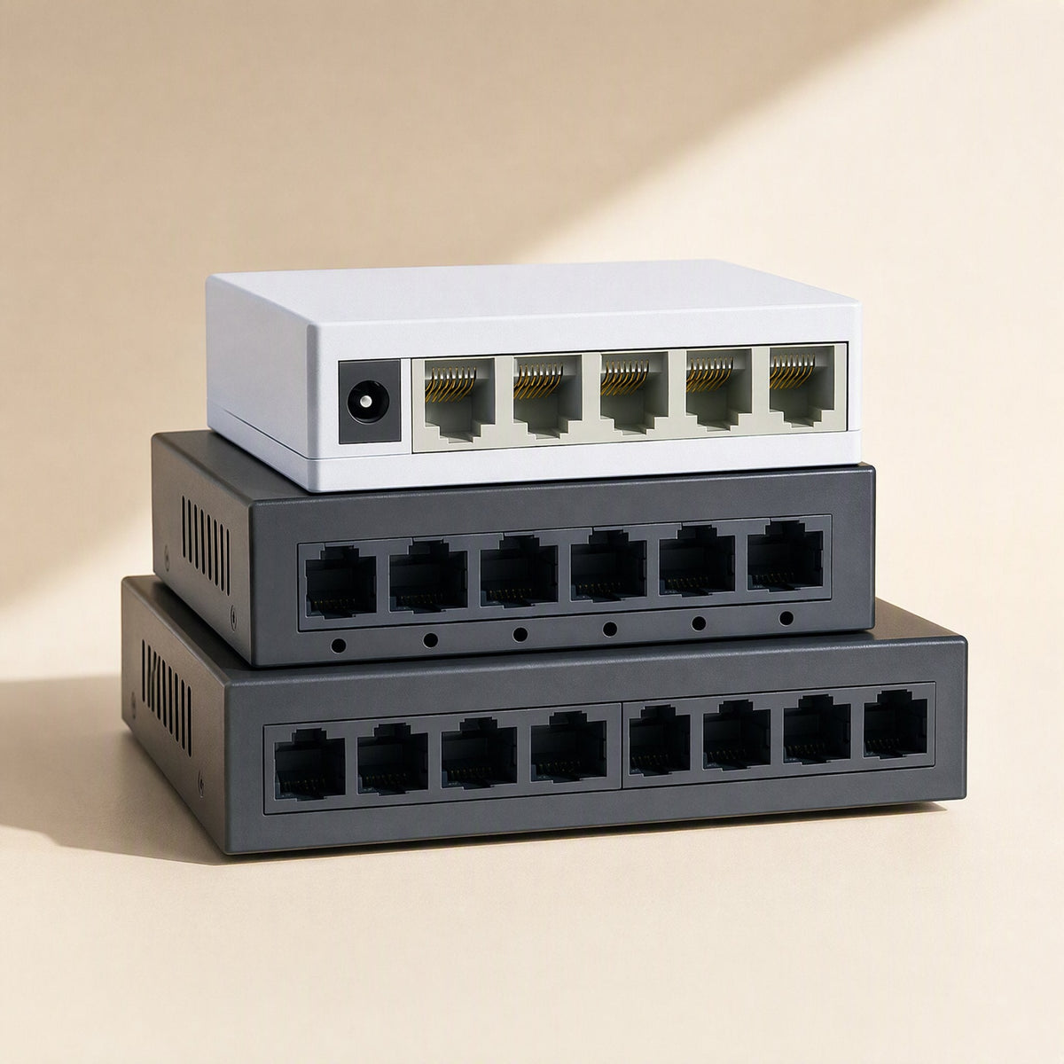 Deskport – Three stacked network switches in white and gray, angled view showing port rows and ventilation slots