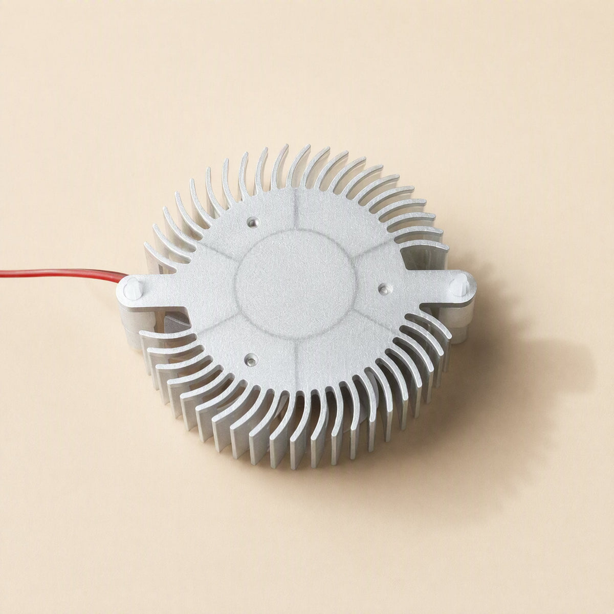 Cardcool – Underside of the round aluminum heatsink showing flat base plate, screw holes and a red wire