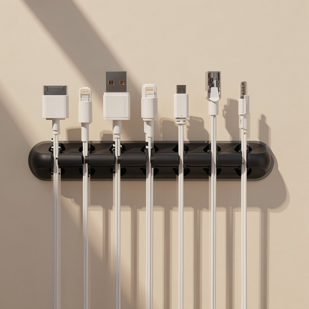 Silinest – Wall-mounted black organizer holding seven white cables, including 30-pin, Lightning, USB-A and audio plugs