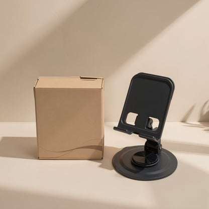 Foldmate Foldable Metal Phone Stand in black with a round swivel base beside a kraft cardboard box