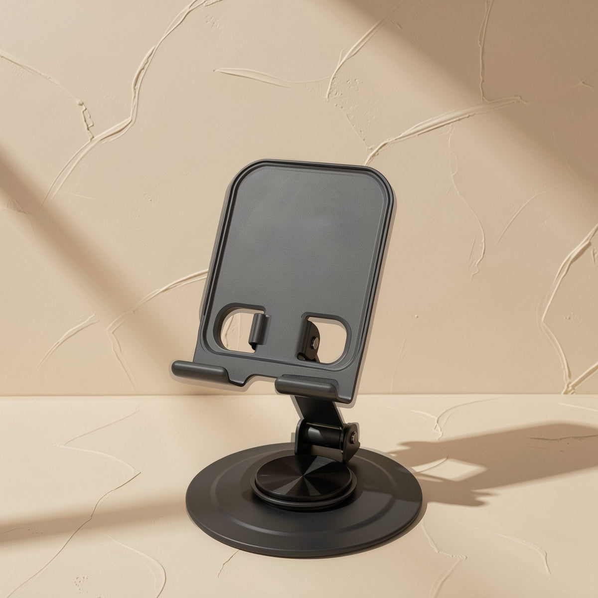 Foldmate – Black phone stand with round swivel base and adjustable arm on a beige textured background