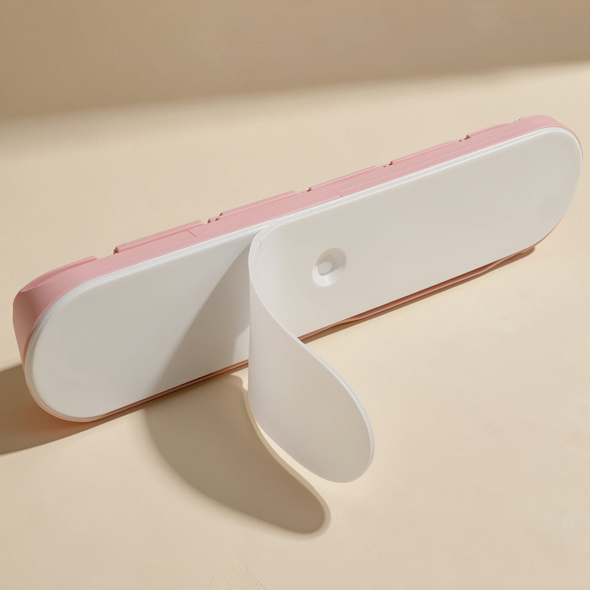 Cordcoil Silicone Data Cable Organizer – white adhesive backing peeled back from the underside of the pink cable organizer