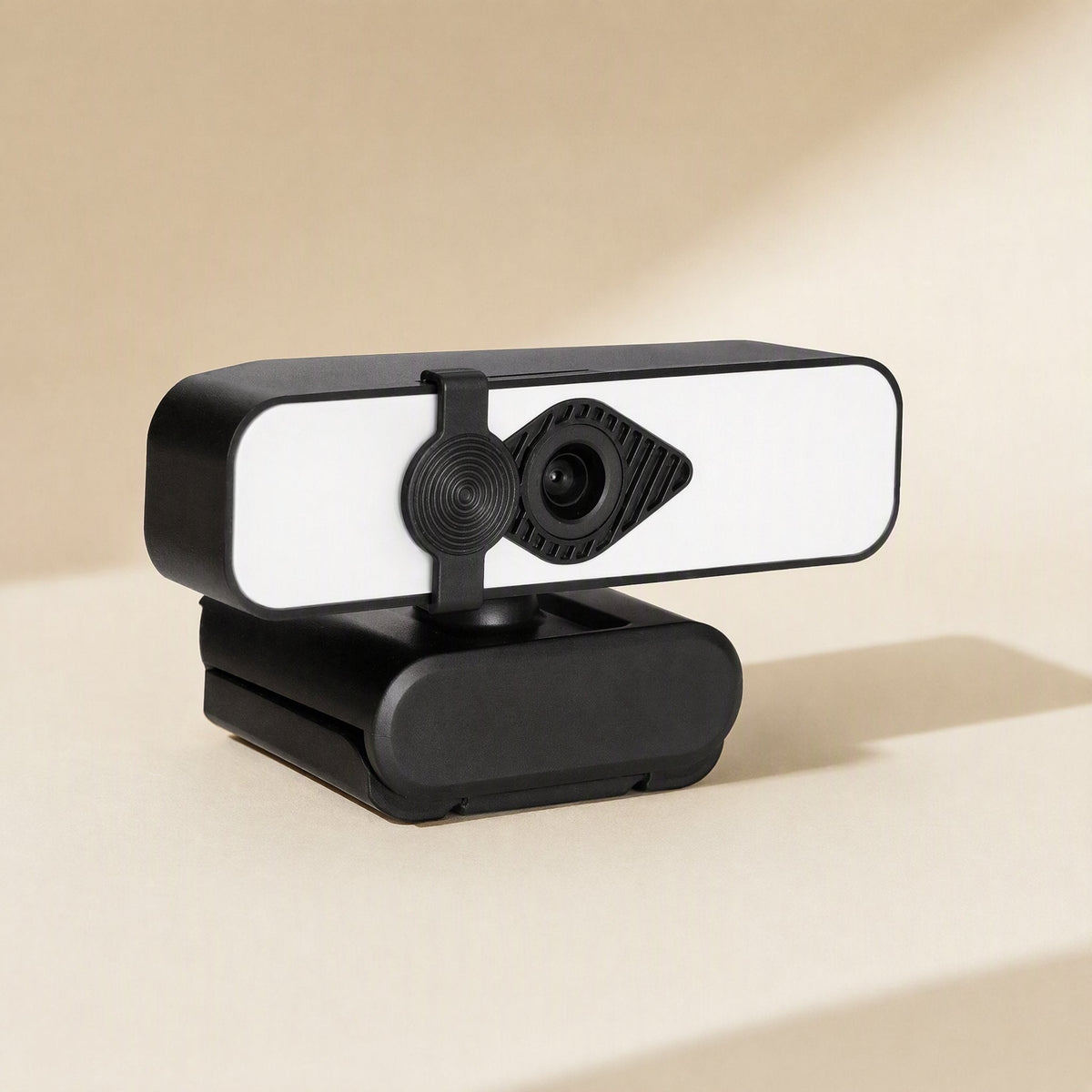 Camclarity – Black webcam with white light bar and round privacy cover, seen from the left side on a cream surface
