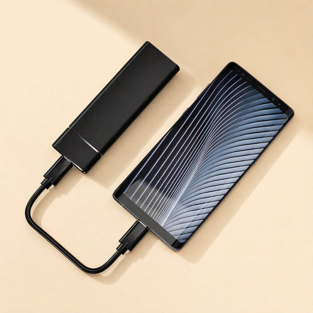 Solidrive – Black portable SSD connected by a short USB-C cable to a smartphone lying beside it on a beige surface
