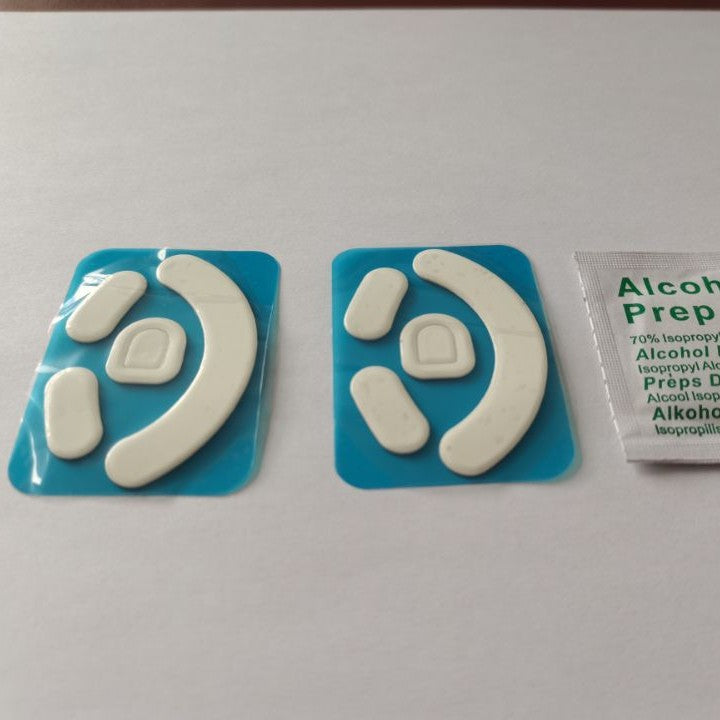Skimfoot Mouse Foot Stickers: two white Teflon sets on blue backing beside an alcohol prep pad