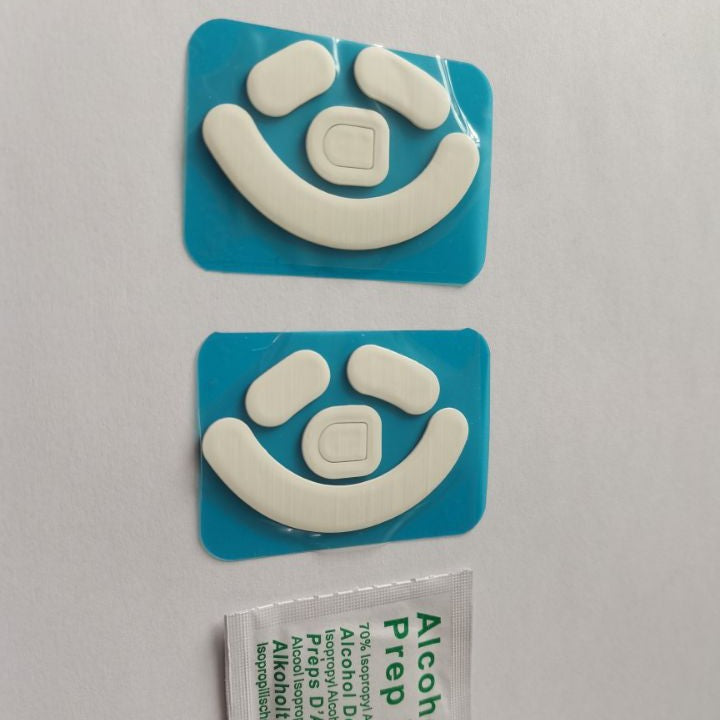 Skimfoot – Top-down view of two white mouse foot sets on blue backing, arcs facing up, with a prep pad at the bottom
