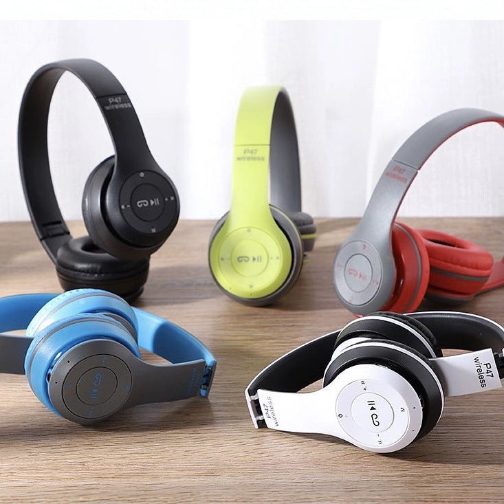 Foldtune – Headphones in black, lime green, gray and red, blue, and white arranged on a wooden surface