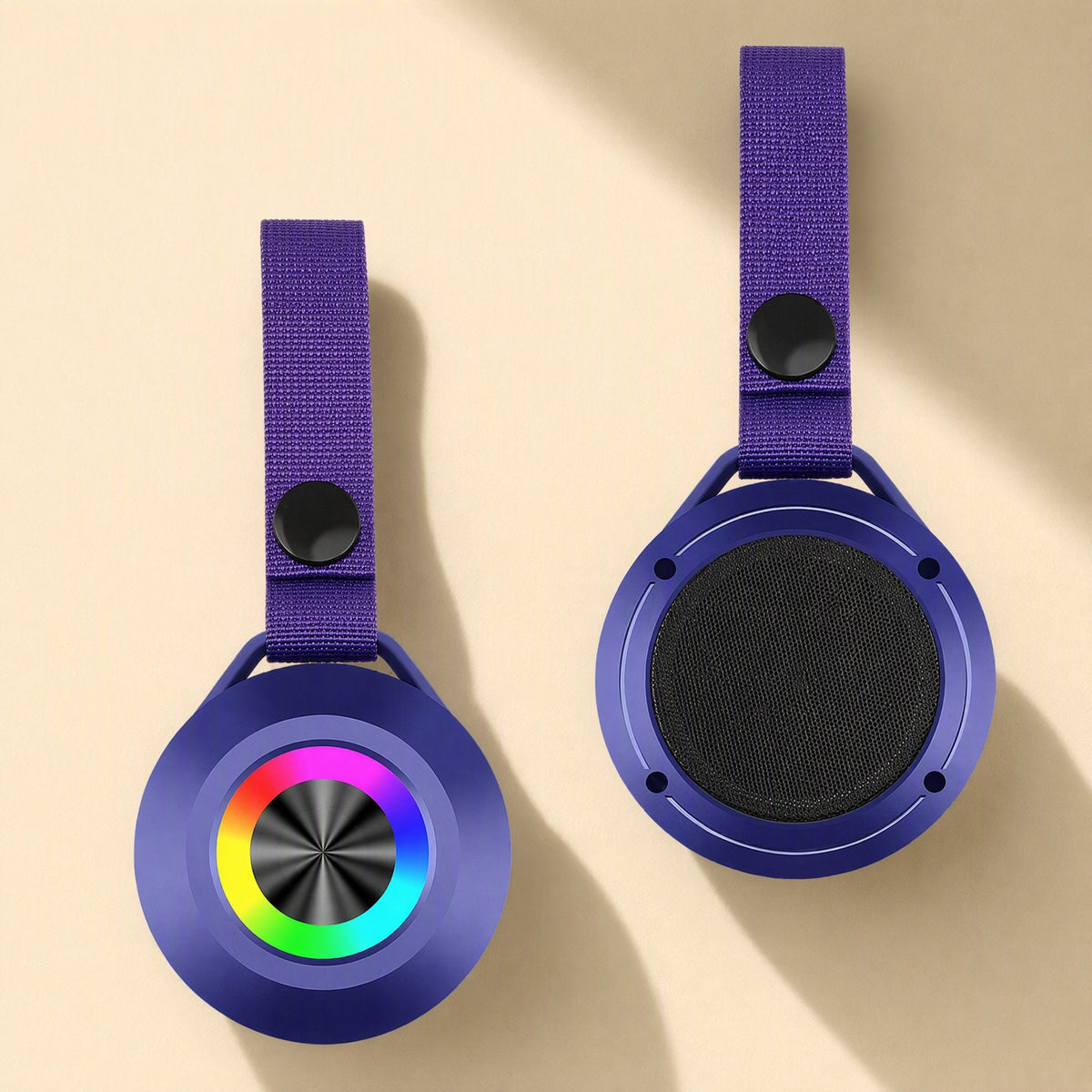Minibeat – Front and back of a purple speaker with a rainbow LED ring, black snap button and mesh grille on a beige