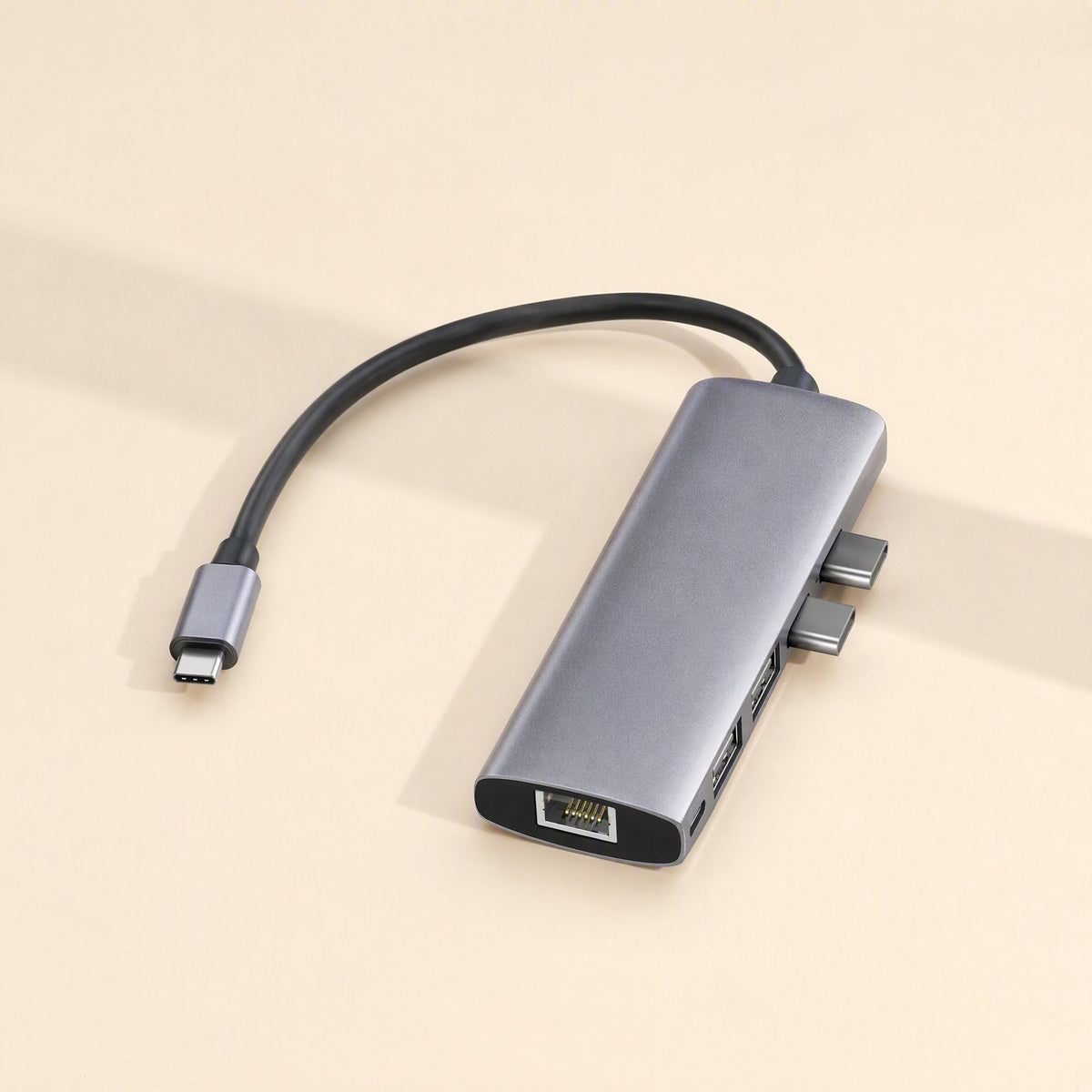 Dockcraft – Gray hub with dual USB-C plugs, Ethernet and USB ports on a warm beige background with shadow