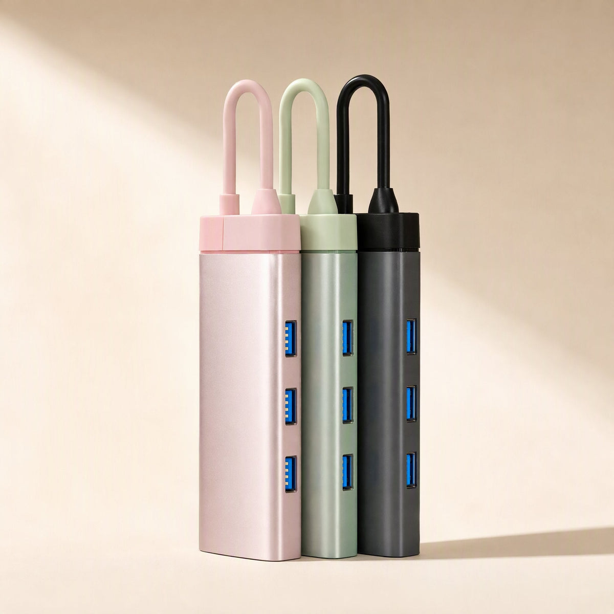 Dockcraft – Pink, sage green and black docks side by side, each with a looped cable and three blue USB-A ports