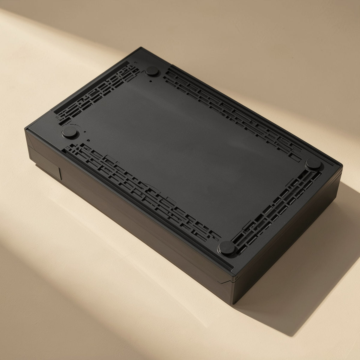 Drivestow – Underside of the black box with four round rubber feet and slotted ventilation along the edges