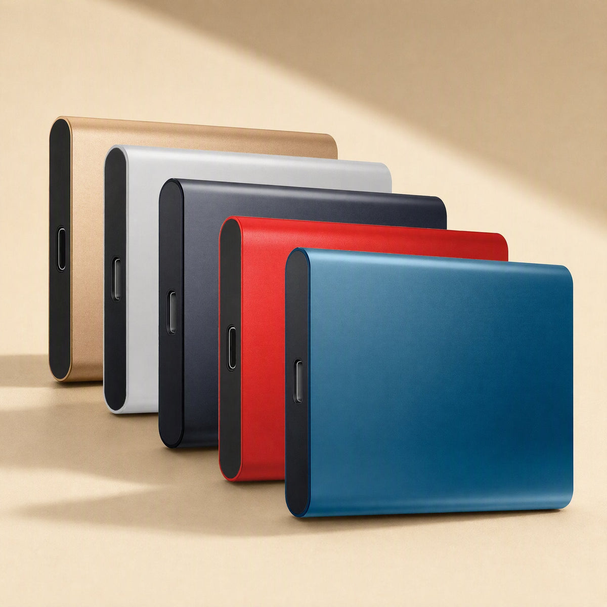 Slimstore Ultra-Thin Solid State Drive in gold, silver, charcoal, red and blue, lined up on a beige backdrop