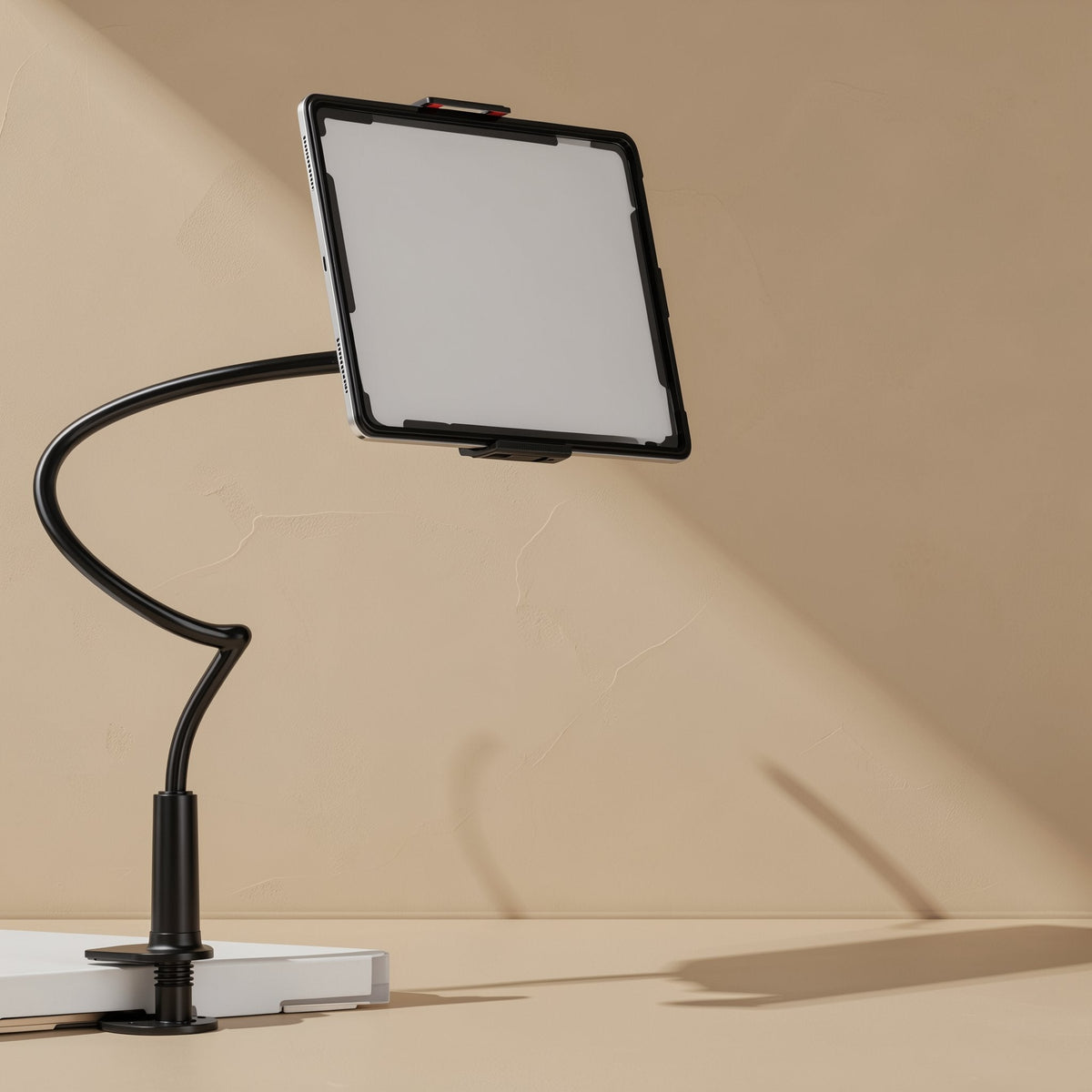 Tiltprop – Black gooseneck stand clamped to a table edge, holding a tablet with a blank white screen