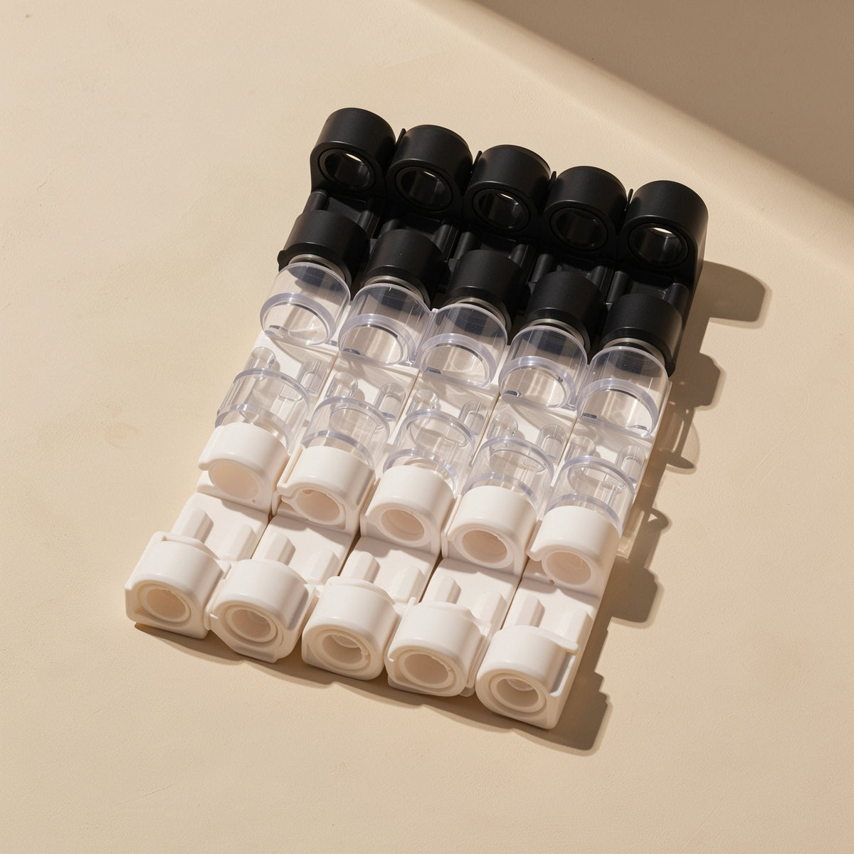 Stickloop – Rows of black, clear and white cable clips laid out flat in five columns on a cream background