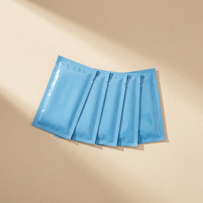 Chilldots Hydrogel Cooling Stickers – five glossy blue foil pouches overlapping in a row on a sand-colored background