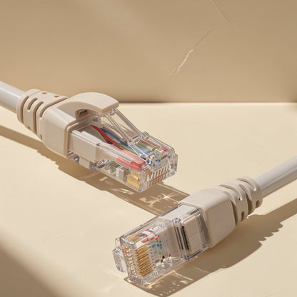 Linklane – Two clear RJ-45 connectors with gold contacts and beige strain relief boots lying on a cream surface