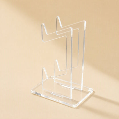 Padstand – Side-angle view of the empty transparent two-tier stand on a rectangular base against a cream backdrop