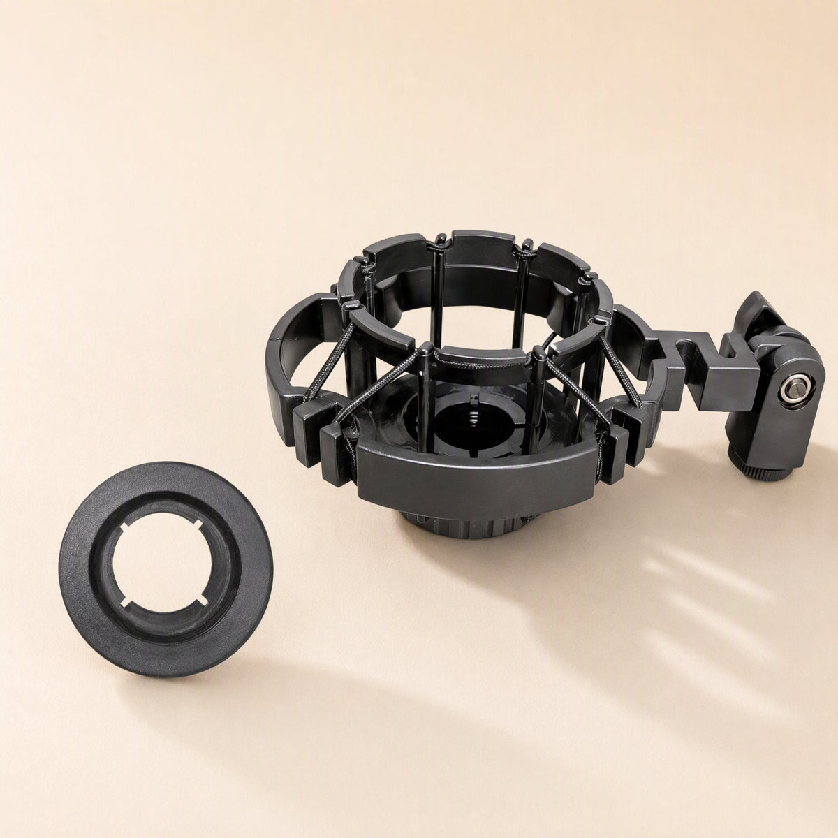Shockgrip – Black suspension mount with elastic bands beside a separate round foam-lined adapter ring
