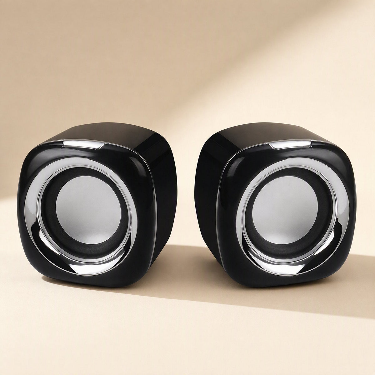 Deskvoice – Pair of black cube-shaped desktop speakers with silver rings around the round grey drivers, front view