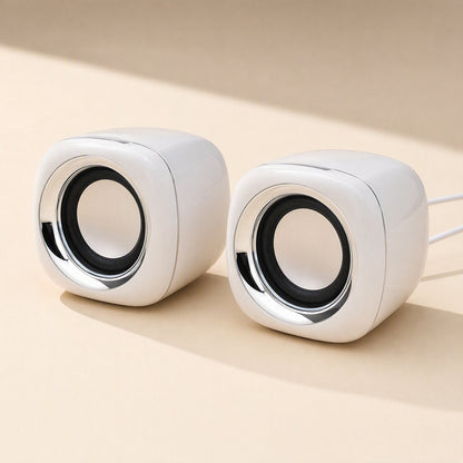 Deskvoice – White cube speakers side by side with chrome trim, a thin cable trailing from the right speaker