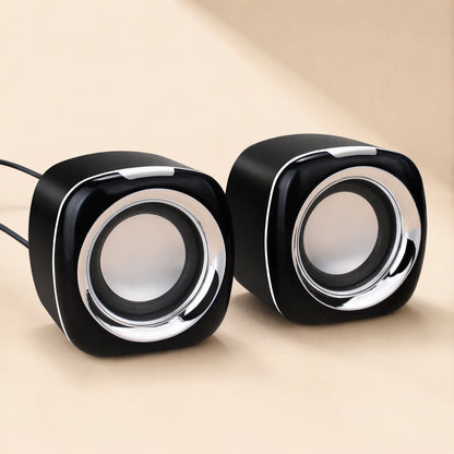 Deskvoice – Black desktop speakers angled to the side with silver edge trim and cables coming out of the left unit