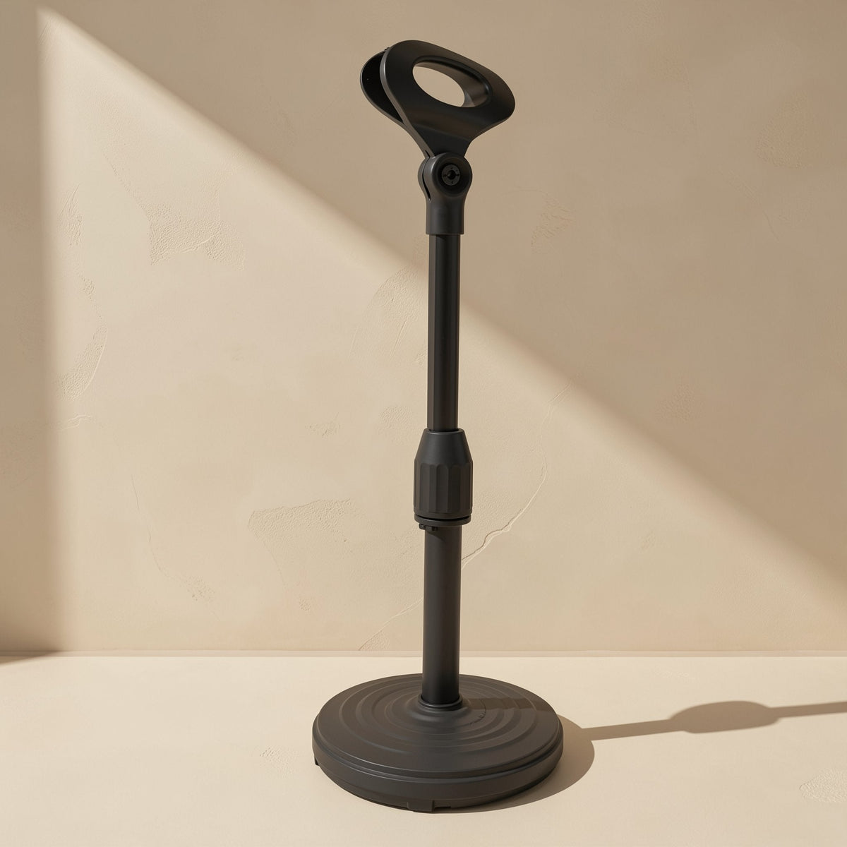 Deskrest – Black telescopic desktop stand with an empty mic clip on top, shown extended on a beige surface