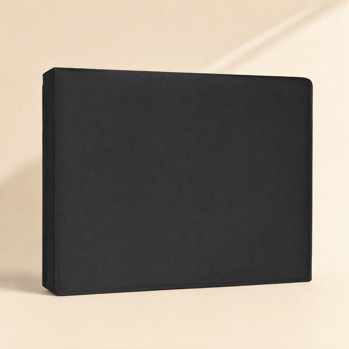 Coverloom Monitor Dust Cover in black oxford cloth standing upright on a cream background